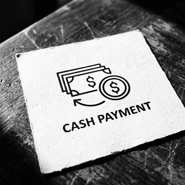 Cash payment icon and text printed on square white paper over dark rustic wooden table for finance and retail business concept.