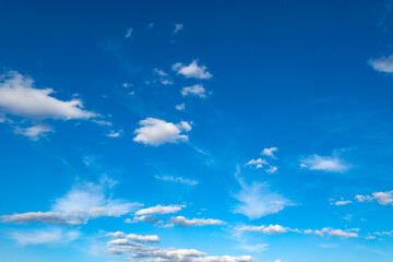Soft white clouds drift across a bright blue sky. © Shutter & Pixel Co.