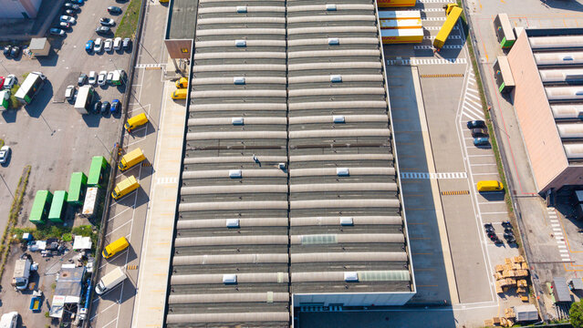 San Giuliano Milanese, Italy - 04 September 2026: Aerial view of Filiale DHL Express with yellow delivery trucks parked in the loading bays and surrounding parking areas.