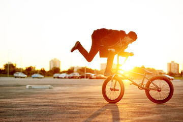 Naklejka premium City, sunset and trick with man on bicycle for adrenaline, exercise or extreme sports outdoor. Bike, flare and training with BMX rider on street in urban town for action, balance or hobby practice