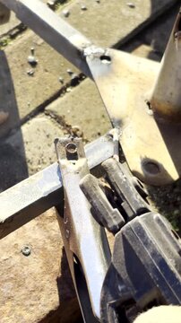Vertical POV. Stick welding to connect pieces of metal together with blue sparks