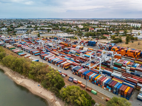 Budapest, Pest County, Hungary - 29 August 2026: Aerial view of Maersk cargo containers stacked at an intermodal terminal, with gantry cranes and rail tracks beside the Danube.