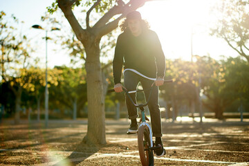 Naklejka premium BMX, man and bike at park for sports, eco friendly travel or exercise with trip. Person, riding bicycle and cyclist on road outdoor for fitness, cycling and sustainable transport in nature with flare