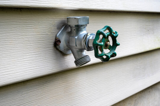 exterior water spigot on siding closeup. Exterior plumbing fixture house