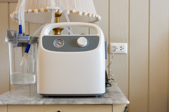 Portable Phlegm Suction, Sputum suction machine from a tube in the throat of a patient who has undergone a tracheostomy surgery in home.