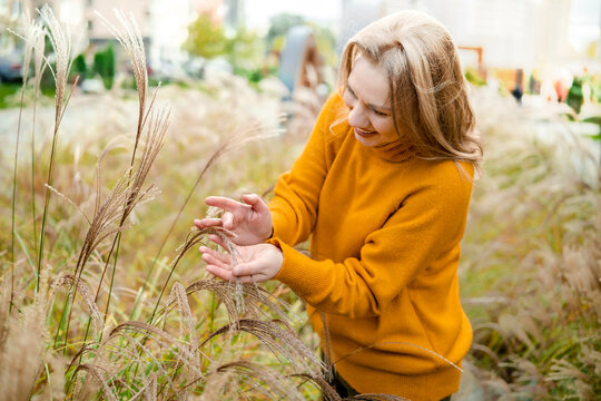 Cheerful woman in autumn nature with tall grass &mdash; mental wellbeing and ecotherapy concept. Joyful person enjoying fall season outdoor walk. Mindful connection with natural environment.