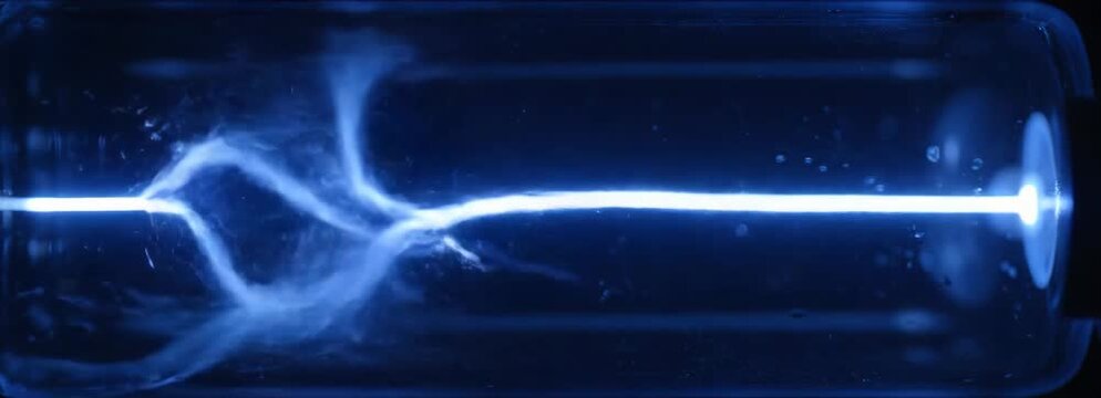 Vibrant blue plasma beam and electrical discharge in a scientific glass tube.