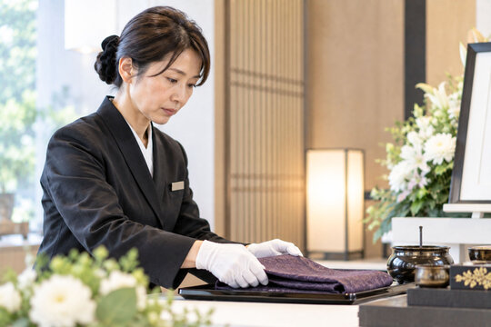 葬儀場で祭壇を整える日本人女性スタッフ