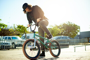 Naklejka premium Man, cyclist and bicycle for outdoor hobby, activity or challenge in skate park. Bike, person and urban sport for cycling, BMX training and skills for competition with balance and stunt exercise