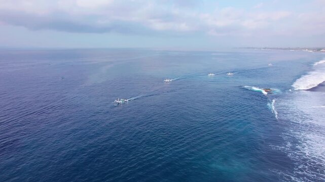 Aerial view of Pantai Wates Yeh Malet with traditional fishing boats on the blue ocean and black sand beach in Kecamatan Karangasem, Bali, Indonesia.