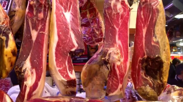 Cured jam&oacute;n legs hanging in a bustling market stall as a gloved hand carves thin slices with a long knife