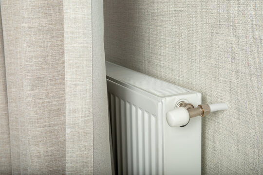 Heating season. Radiator positioned discreetly behind curtain provides warmth in winter
