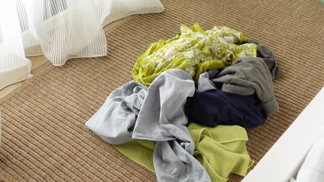 A disorganized pile of clothes is scattered on the carpet in the room