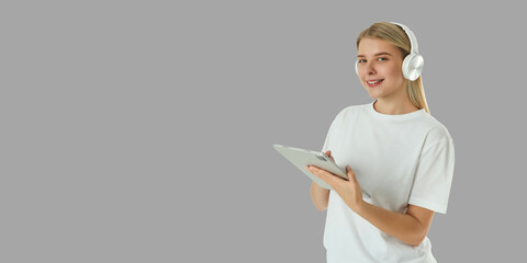Smiling young woman interacts with tablet while wearing headphones © Atlas