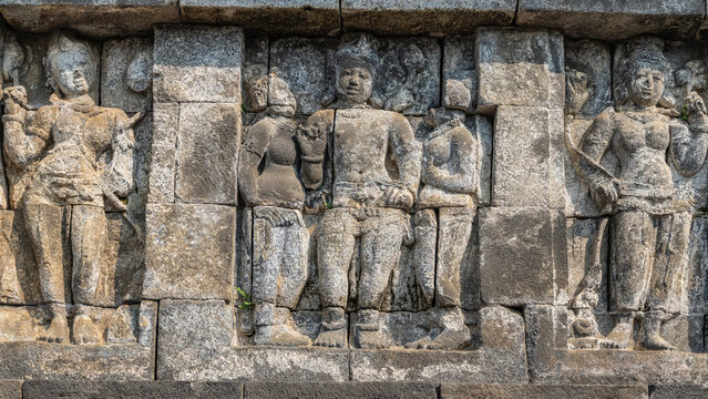 Ancient Hindu art. Details. On the stone wall, there are beautiful carved bas‑reliefs depicting people. Fragment. Indonesia. Java. Yogyakarta. Candi Borobudur Temple