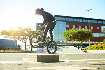Naklejka premium Man, bicycle and jump for outdoor activity, hobby or challenge in skate park. Bike, person and urban sport for cycling, BMX training and skills for competition with balance and stunt exercise