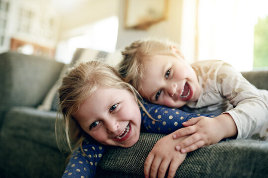 Portrait, siblings and children on sofa, lounge and girls with smile on break, bonding and together. Happy, sisters and relax on couch, home and kids in living room, chill or family in apartment