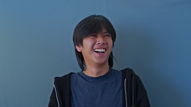 Young man experiencing rapid and erratic emotional mood swings laughing one moment and turning solemn depicting bipolar disorder