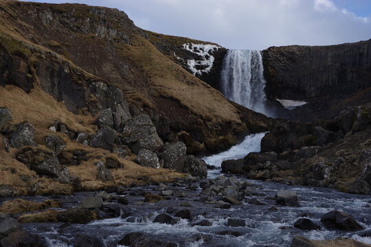 Svodufoss waterfall falling over basalt column cliffs above a rocky river on Snaefellsnes peninsula Iceland