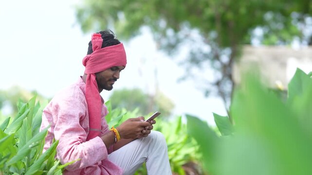 Young indian farmer using smartphone at turmeric agriculture field
