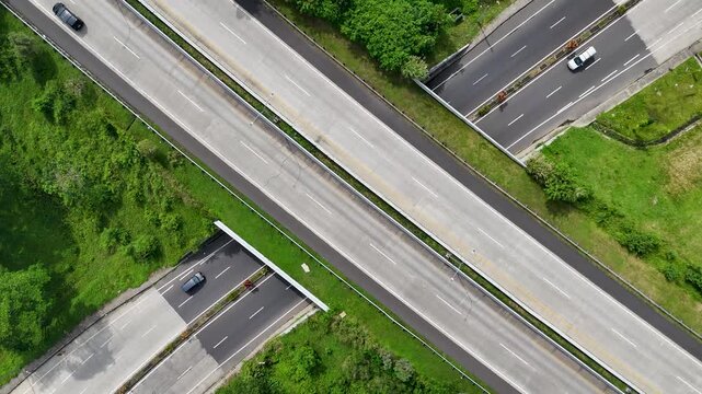 Aerial view of the Soreang highway intersection with vehicles driving on asphalt roads surrounded by lush green vegetation in Bandung, West Java, Indonesia.