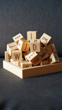 vertical of A stack of wooden alphabet letter blocks isolated on a dark grey background.