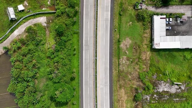 Aerial view of the Soreang highway surrounded by lush green vegetation and rice fields in Bandung, West Java, Indonesia.