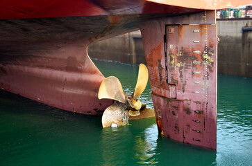 Marine propeller revealed as water is pumped from a dry dock during ship maintenance. © Mariusz