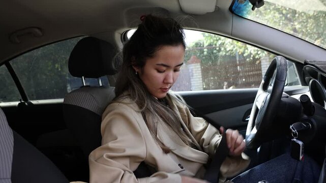 Asian woman fastening seat belt, driver seat of car, vehicle interior, steering wheel, ignition key, manual transmission, road safety , automotive, driving school, insurance