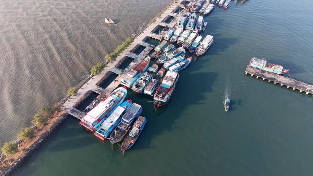 Aerial view of harbor with many boats docked. Water ripples gently as boats sit idle at Probolinggo