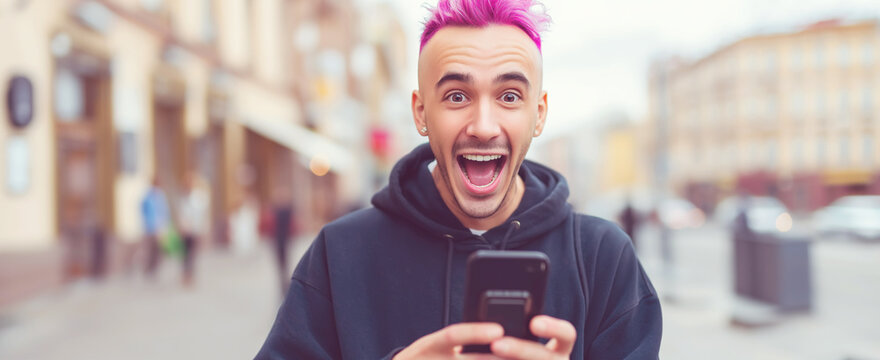 Young man with pink hair reacting with surprise and joy to online content on his smartphone in the city