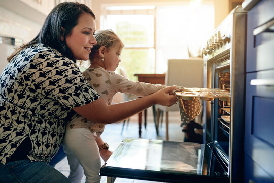 Oven, baking and cupcake with mother and daughter in kitchen for help, cooking and learning. Support, food and teaching with woman and child in family home for dessert, bonding and love together