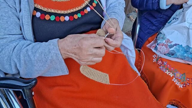 Woman wearing national costume performing traditional hand knitting needlework