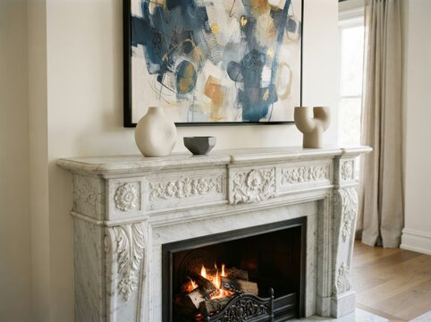 Carved marble fireplace mantel with burning fire and ceramic vases. Large abstract painting above mantel in elegant living room. Luxury interior decor. Classic home design. Cozy ambiance.