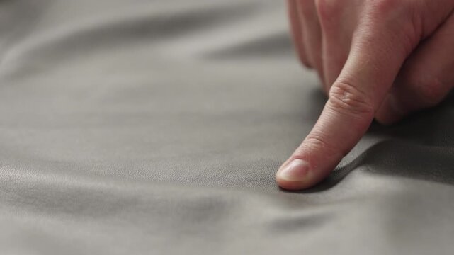 Slow motion man hands inspecting leather jacket before season