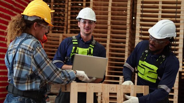 A diverse team of workers collaborates in a large warehouse facility, using a laptop and checking inventory against wooden pallets and stacked cargo boxes.