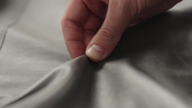 Slow motion man hands inspecting leather jacket before season