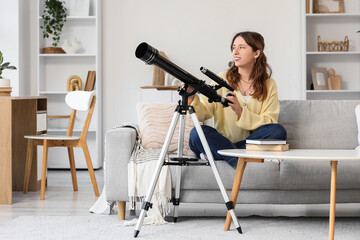 Fototapeta premium Astronomy and curiosity, young woman using a telescope at home for stargazing and science education in a cozy living room interior with modern decor