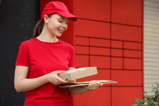 Logistics and parcel delivery service, courier woman holding cardboard box and mail in front of red automated locker for contactless package pickup