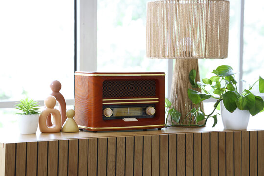 Nostalgia and retro lifestyle, vintage wooden radio on a modern sideboard with houseplant and lamp in a bright living room interior for home decor