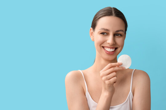 Skincare routine and facial cleansing, young woman holding a cotton pad for makeup removal and skin health on a blue background