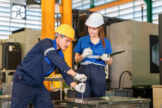 Industrial engineers working together and inspecting machinery in manufacturing plant, Technicians discussing work with clipboard in factory, Factory workers operating equipment in workshop