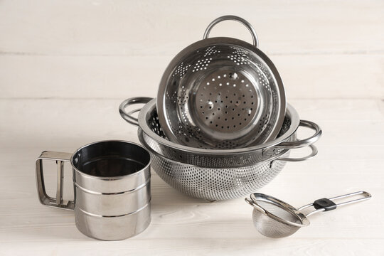 Home cooking and food preparation, stainless steel kitchen colanders and flour sifter on a white wooden table for culinary and baking tasks