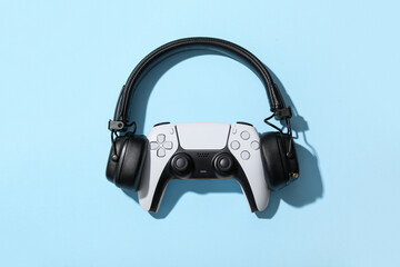 Gaming culture and immersive entertainment, wireless game controller with professional headphones on a blue background for esports and digital media © Pixel-Shot
