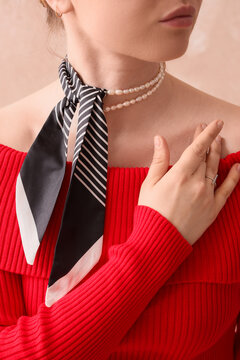 Fashion and elegance concept, woman wearing a striped silk neck scarf and pearl necklace with a red ribbed top for a stylish lifestyle portrait