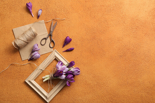 Spring floral arrangement creative hobby and craft with purple crocus flowers vintage scissors and twine on a textured orange background