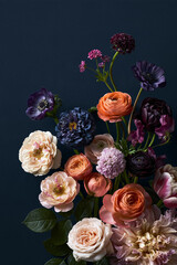 Fototapeta premium Beautiful still life featuring a vibrant bouquet of various colorful flowers, including ranunculus, roses, and anemones, on a dark blue background