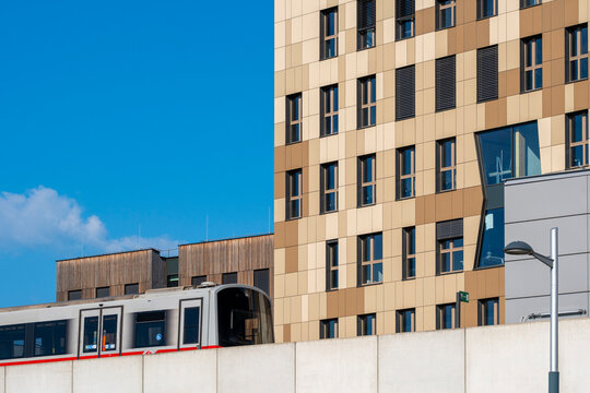 Urban rail train passing modern residential buildings at Aspern Seestadt Vienna Austria showing public transport and transit integrated with housing
