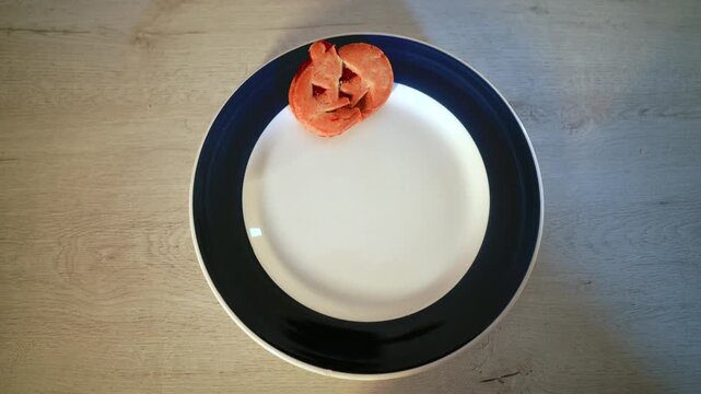 Top down view of a female hand carefully arranging spooky homemade cookies shaped like jack o' lanterns and ghosts on a white and blue plate, preparing a festive treat for a halloween party