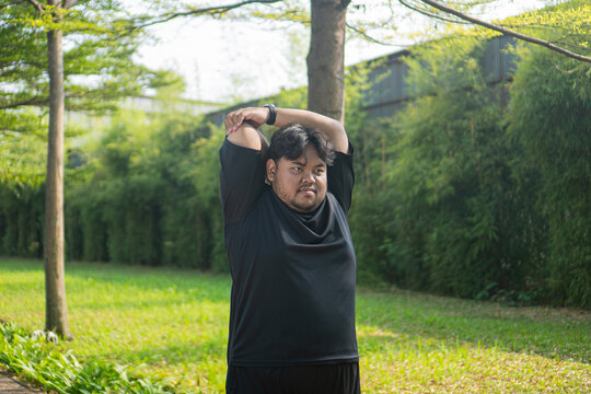 Man stretching overhead in a park before exercising